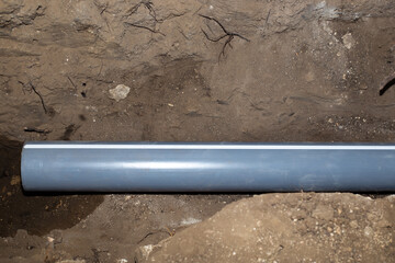 a plastic drainage pipe lies in a dug trench,construction and communications