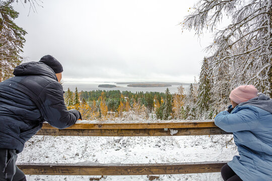 A man and a woman on the observation tower, look at the winter, landscape. Forest in the snow and the sea in the distance