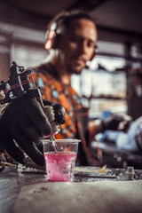 Hand of professional tattooer and a tattoo gun.