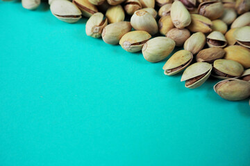 many grains of pistachios close-up top view on turquoise background