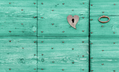 Close-up of an old wooden turquoise-colored exterior door with an iron handle and a lock