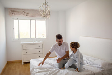 Fototapeta premium Dad And Sons Playing. A Dad And His Sons Play Games On The Bed. Lifestyle Family.