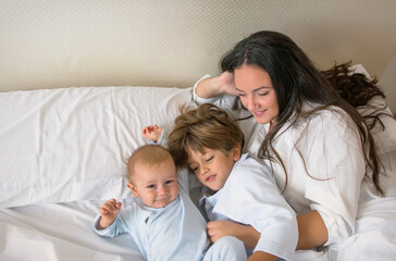 Fototapeta na wymiar Mom And Children Playing. A Mother And Her Children Play In Bed. Family Lifestyle.