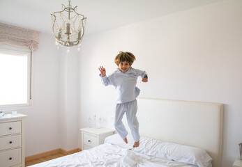 Boy Jumping On The Bed In Pajamas. Family Lifestyle
