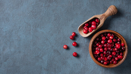 fresh and sweet cranberries in a wooden bowl on a dark blue wooden background