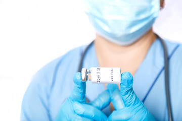 A vial with a coronavirus vaccine in the hands of a masked doctor.