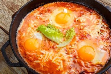 israeli fried eggs shakshuka in a frying pan on a wooden table on a stand