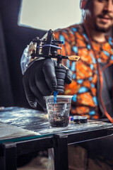 Hand of professional tattooist and a tattoo machine.