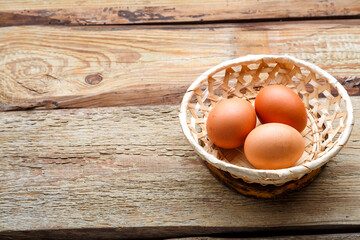 Brown chicken eggs in a wicker plate on a wooden table. horizontal