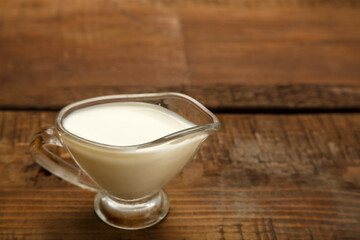 A jug of transparent cream for the sauce on a wooden table.