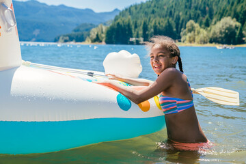 Smiling happy girl in bikini swimming in lake with pool floaty