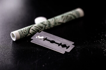 money banknote rolled up with pills and a razor blade, concept of drug use, cocaine