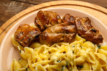 A plate of pasta in a creamy sauce with cheese and chicken.