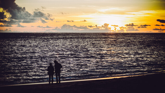 pareja contempla el atardecer maritimo en una playa de carvoeiro, portugal
