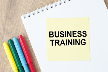 Business Training is written on yellow paper for notes on the table next to colored markers and a notebook.