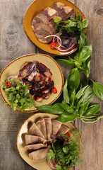 Oriental cuisine. Meat snack. Kazy. Homemade boiled horsemeat sausage with spices and fresh herbs. Beef tongue with onion and chili pepper. Rustic. Background image, copy space. Top view, flatlay