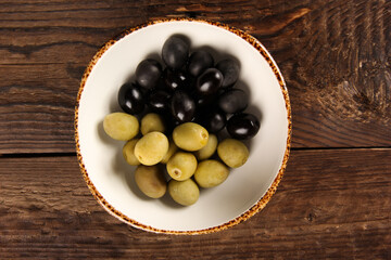 Snacks. White plate with olives on a wooden table. Rustic. Background image, copy space. Top view, flatlay