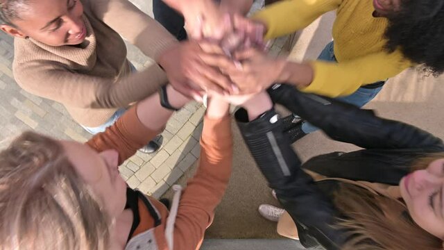 An overhead view of the hands of friends or colleagues from different cultures and nationalities stacking together and shaking them