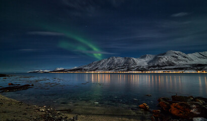 aurora borealis above the Norwegian fjord, reflection of the Lyngen Alps, winter scenery of the Norwegian mountains illuminated by aurora borealis, - 389965528