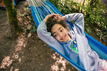 Happy, smiling girl relaxing in hammock in forest campground