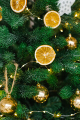 Fototapeta na wymiar The Christmas tree is decorated with toys, dried lemons or oranges, Golden balls, white eggs and garlands in close-up.