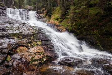 Fototapeta na wymiar spectacular long waterfall in the forest, water cascades over the rocks, bohemian forest