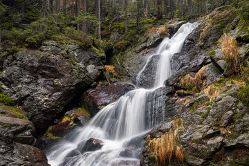 waterfall cascades in the rock in autumn forest, bohemian forest, germany