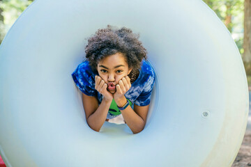 Happy teen girl playing with innertube in forest campground making funny face