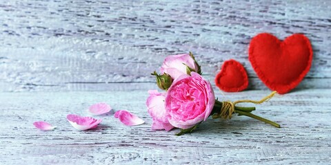 
A small bunch of fresh roses, a pair of red felt hearts on a wooden surface, background for romantic congratulations, postcard - Powered by Adobe