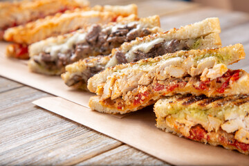 A view of several slices of panini sandwiches on a wooden surface.