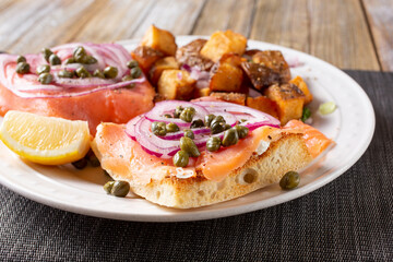 A view of a plate of an open sandwich of lox on ciabatta.