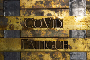 Covid Fatigue text message on textured grunge copper and vintage gold background