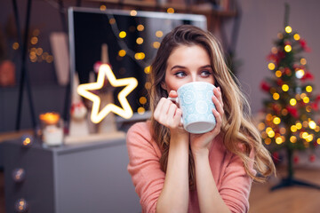 Beautiful young smiling woman at Christmas drinking a cup of tea