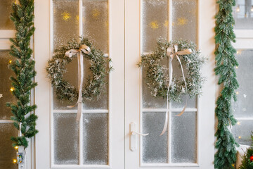 White wooden door with a Christmas tree wreath hanging © Sunshine