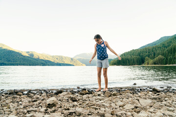 Girl walking along the rocky beach of lake in the mountains