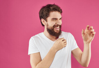 Enthusiastic man in a white T-shirt with a bushy beard on a pink background