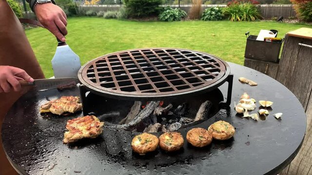 Caucasian man In leather tablier grilling beef steaks on a barbecue outdoor grill. Barbeque autumn time.