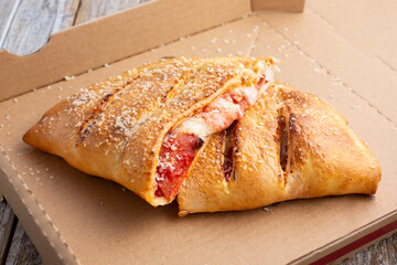 A view of a half cut calzone inside a cardboard pizza box.