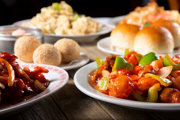 A view of several Chinese entrees and dumpling appetizers on a table.