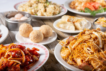 A view of several Chinese entrees and dumpling appetizers on a table.