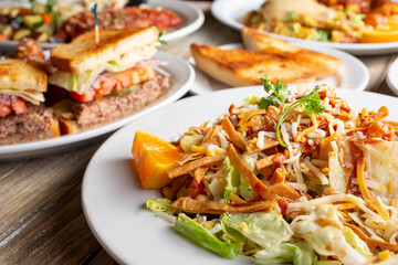 A view of several prepared entrees, featuring a plate of BBQ chicken salad, in a restaurant or kitchen setting.
