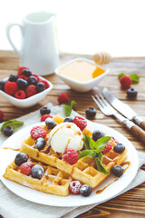 Tasty waffles with fresh berries and ice cream on brown wooden background