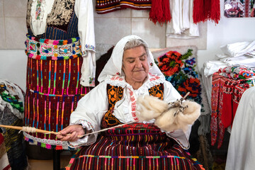 An old woman weaver spun wool on her hand