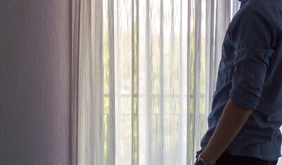 Retrato de la figura de un hombre caucásico elegante posando junto a una brillante e iluminada ventana en un día soleado mientras bebe café y trabaja desde su celular.  - obrazy, fototapety, plakaty