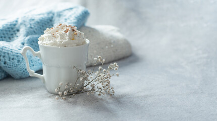 cozy winter composition with cup of hot chocolate, hot cooca cup with knitted sweater and ball lights, girly winter aesthetic photography, blue and white hues and airy atmosphere