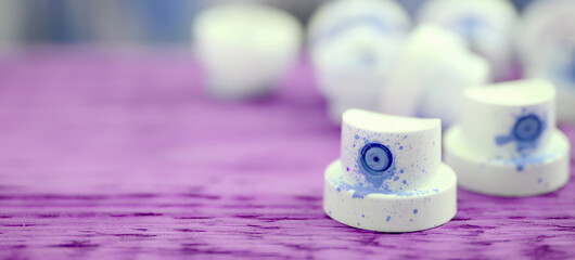 The soiled blue nozzles from the paint sprayer lies on a purple plank on a background of a many...