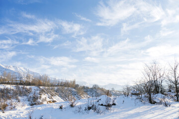 Snowy beautiful winter landscape of the Tien Shan mountains in Uzbekistan on a frosty Sunny day with blue sky and Cirrus clouds. Chimgan