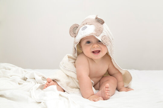 Beautiful and adorable baby smiling just out of bathing. He is wrapped with a towel with bear hood.