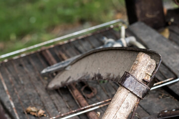 Old scythe leaning against a metal grid. Shallow DOF