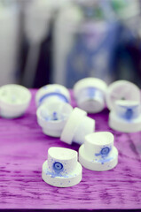 The soiled blue nozzles from the paint sprayer lies on a purple plank on a background of a many...